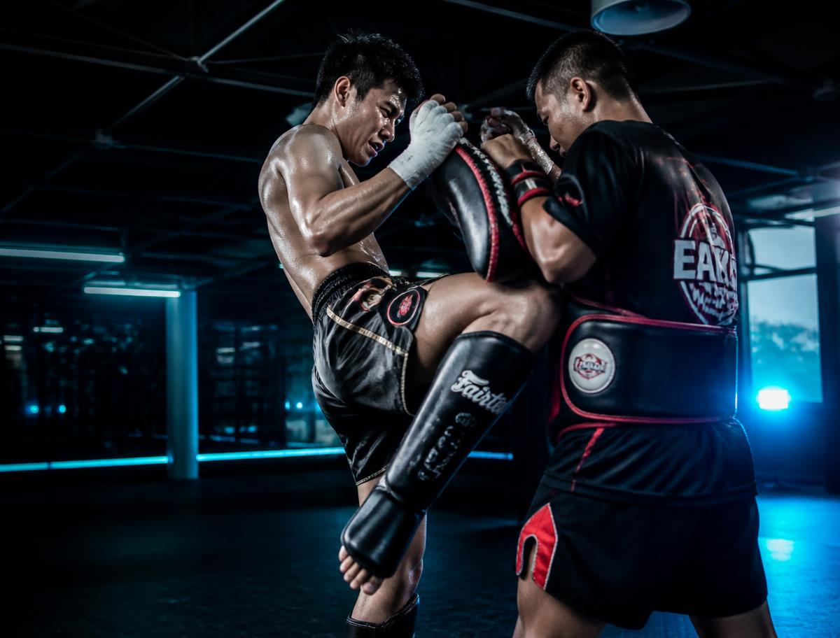 Adult kickboxing student landing a knee on pads during class at TD Athletics Brooklyn